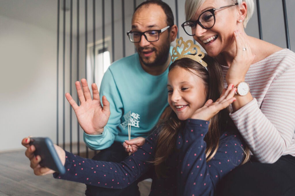 Eine Familie winkt beim Video-Anruf ihren Großeltern zu